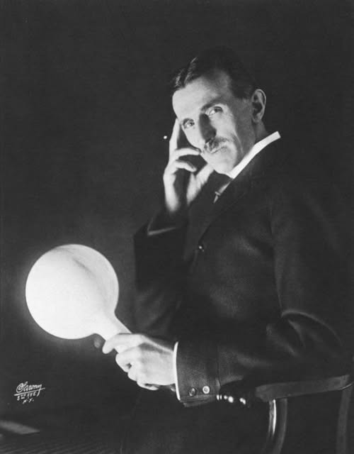 Nikola Tesla holding a gas-filled phosphor-coated wireless light bulb which he developed in the 1890s, half a century before fluorescent lamps came into use.
